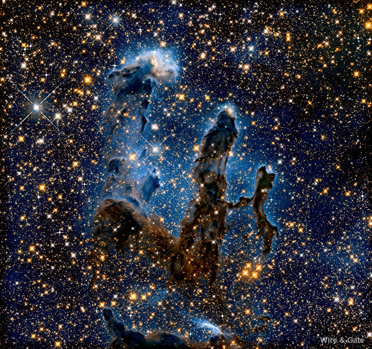 Trois colonnes de gaz sombre aux bords bleutés, dressées dans un champ d’étoiles orangées